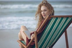 Mujer sentada en una tumbona sosteniendo un libro